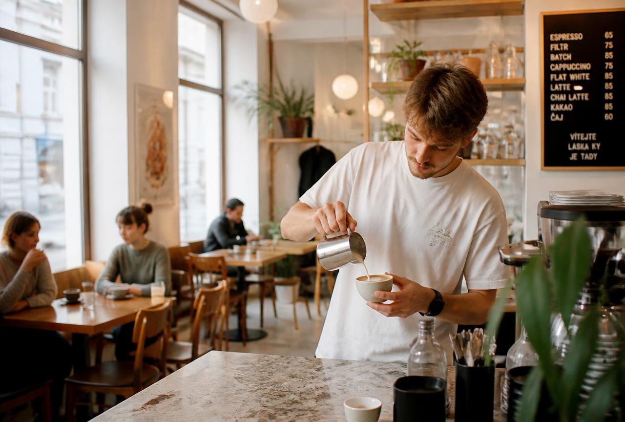A specialty coffee bar in central Brno with daylight and locals at wooden tables